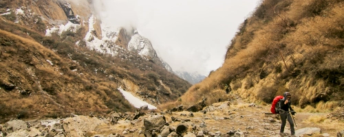 A lone trekker walking through a rugged mountain valley.