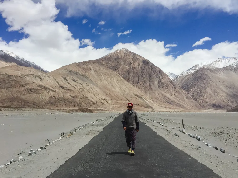 Traveler walking on a road surrounded by mountains in Ladakh.