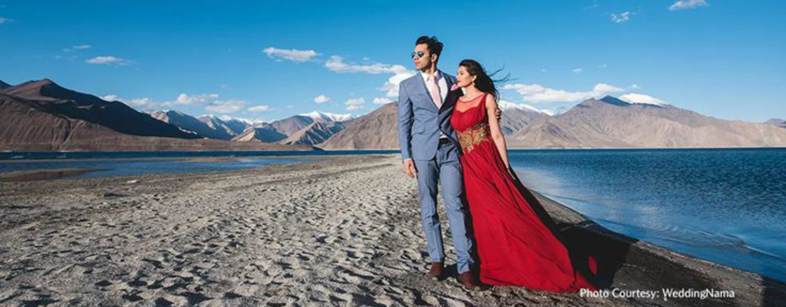 Couple posing by Pangong Lake in Ladakh with mountains and blue sky background www.triphills.com