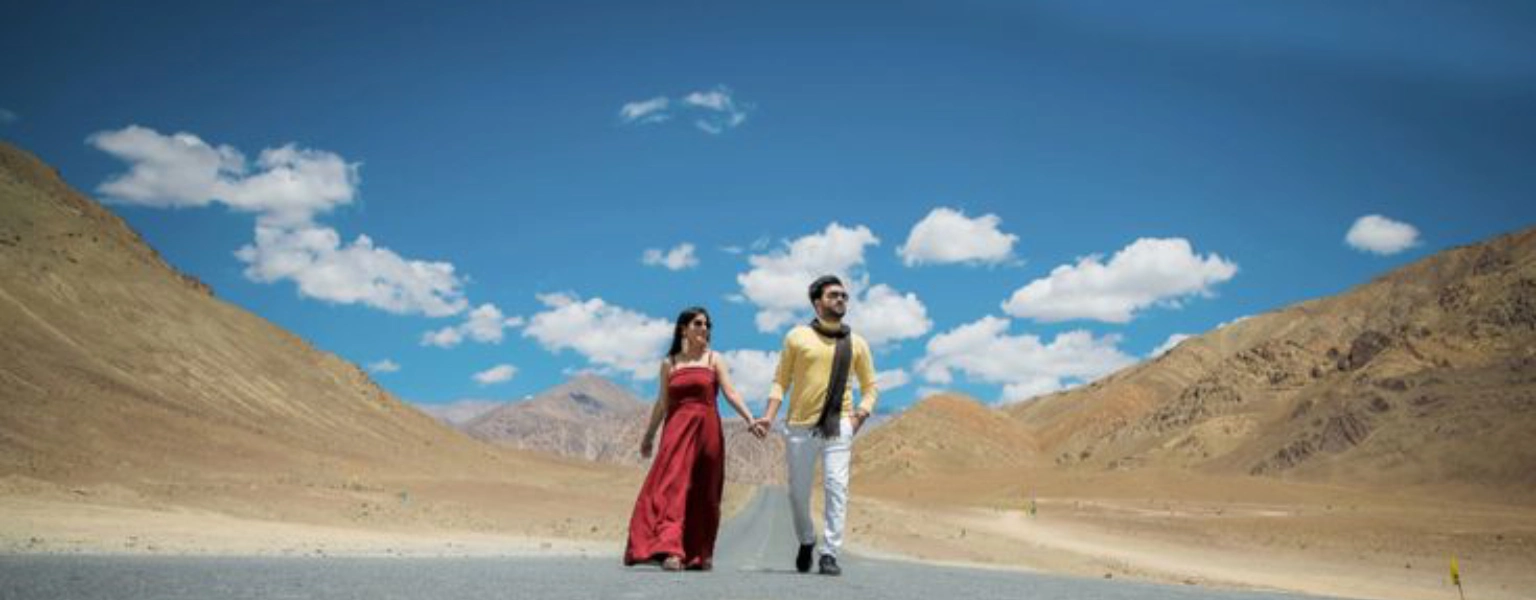 Couple walking hand in hand on an empty road in Ladakh mountains under blue sky