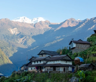Traditional village houses nestled in the mountains with snow-capped peaks in the background in Sikkim.