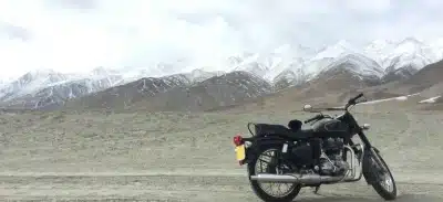 Motorcycle parked in Ladakh with snow-covered mountains in the background.
