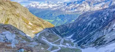 A winding mountain road cutting through a deep Himalayan valley.