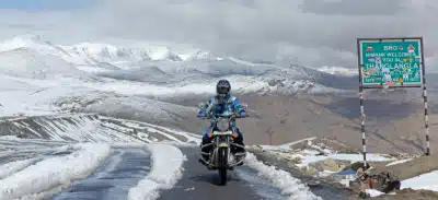 Motorcyclist riding through a snowy mountain pass in Ladakh.
