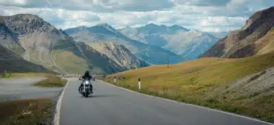 Motorcyclist riding on a scenic mountain road surrounded by valleys and peaks.